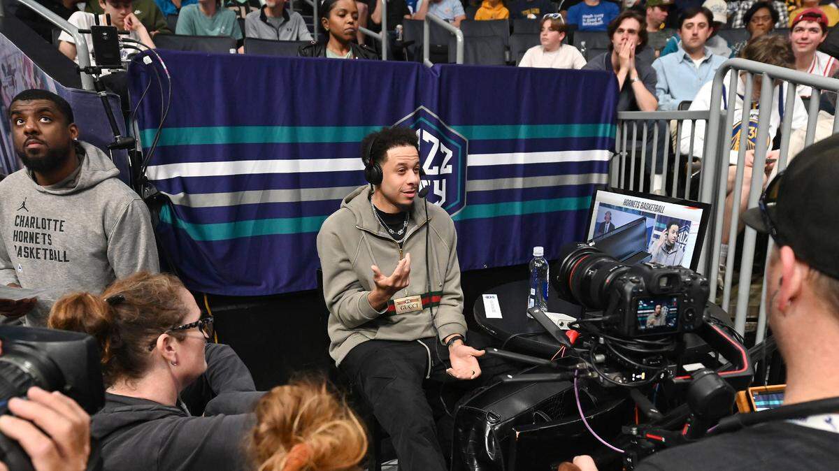 Injured Charlotte Hornets guard Seth Curry, center, is interviewed during a timeout in second quarter action of the team’s game against the Golden State Warriors at Spectrum Center in Charlotte, NC on Friday, March 29, 2024.