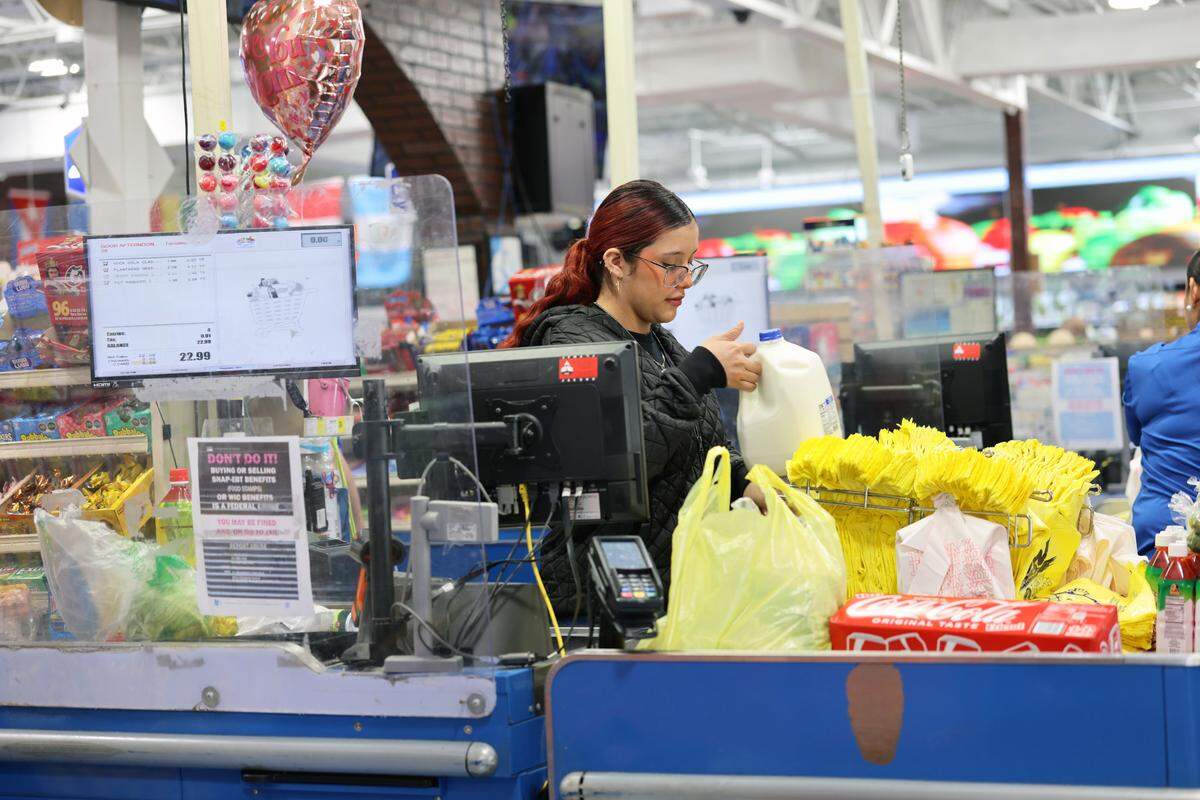 A 28-year-old cashier at Wow Supermarket sought asylum in the U.S. after her father died in Honduras. She assists customers dealing with rising grocery costs due to international tariffs on Tuesday, May 20, 2025.