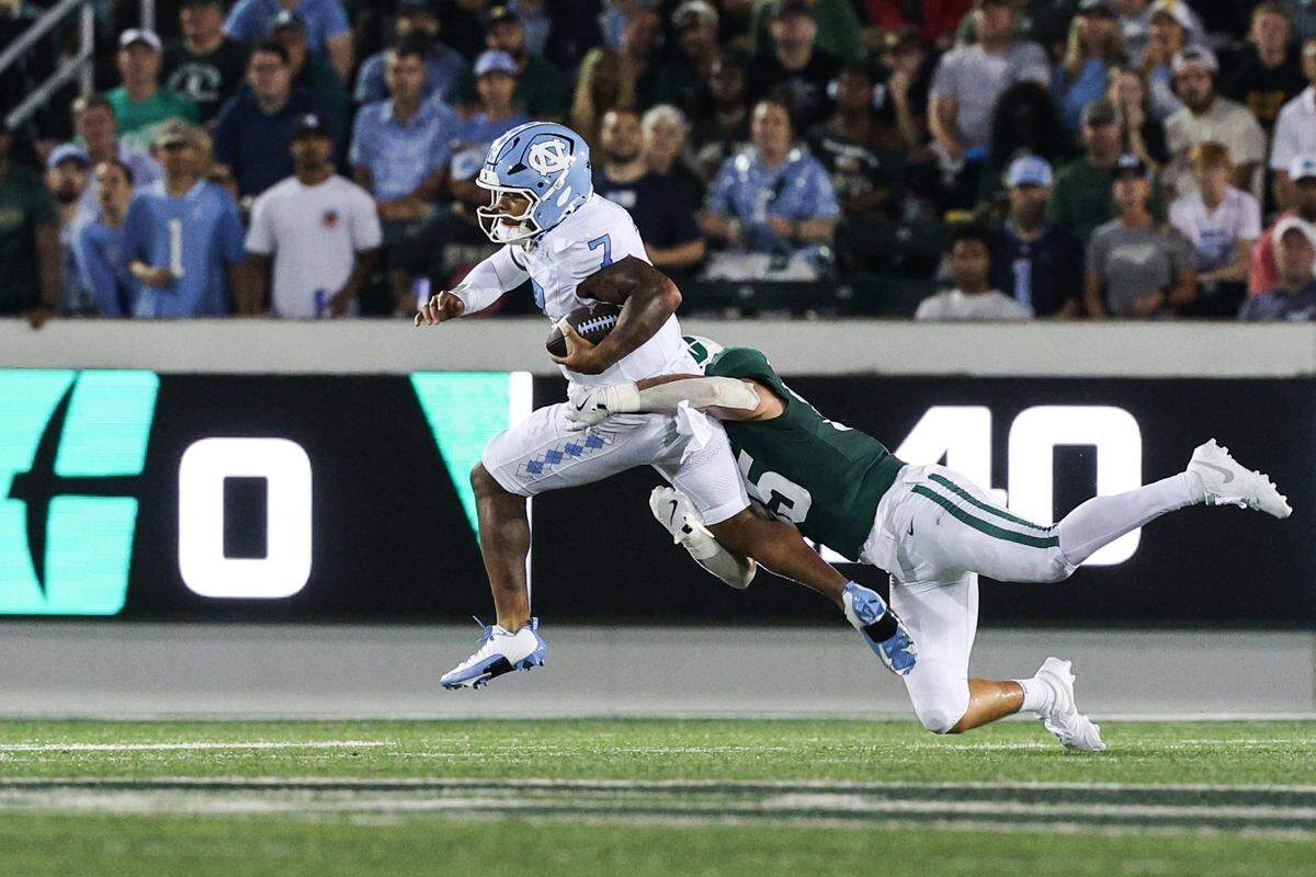 Charlotte linebacker Shay Taylor, right, hangs onto UNC quarterback Gio Lopez as he runs the ball during the game at Jerry Richardson Stadium in Charlotte on Saturday, September 6, 2025.