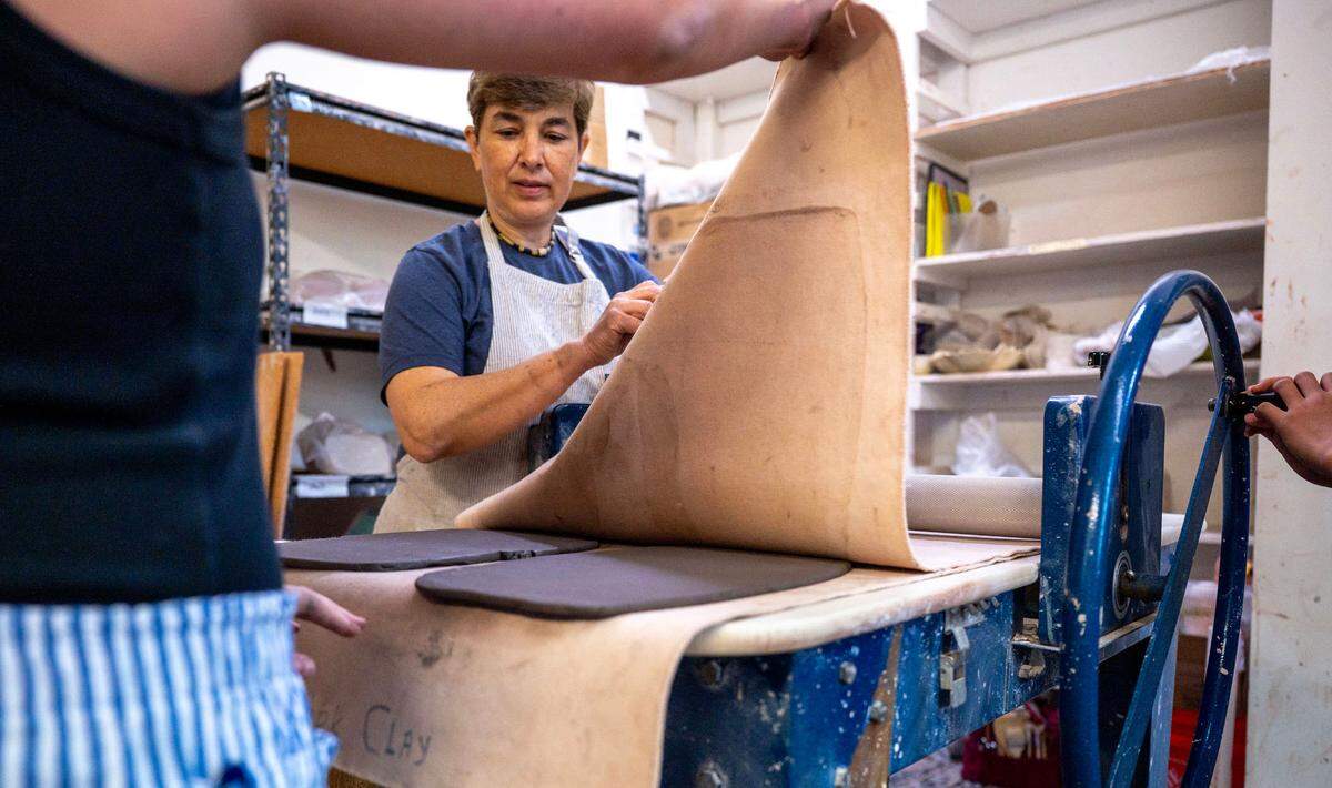 Pottery teacher Taisia Ealy helps campers Katie Kim and Harper Reed extract their clay slabs from the slab roller. Ealy is excited for the ceramic studio to have a permanent home soon with the move to the historic Perry Goodrum and Gabriel-Puckett houses.