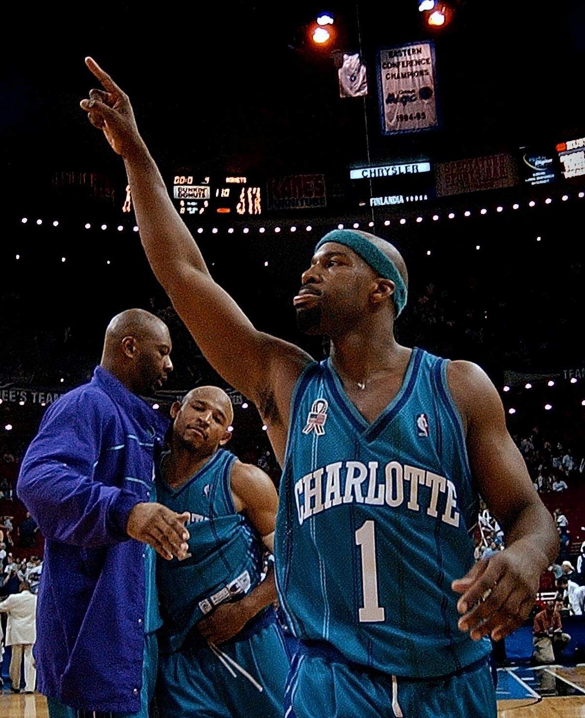 Charlotte Hornet’s Baron Davis celebrates with teammates ELden Campbell and David Wesley after the Hornets beat the Orlando Magic 100-110 in overtime during Game 3 of the Eastern Conference Playoffs on April 27, 2002, at the TD Waterhouse Center in Orlando, FL. Baron Davis had a triple-double and finished with 33-points.