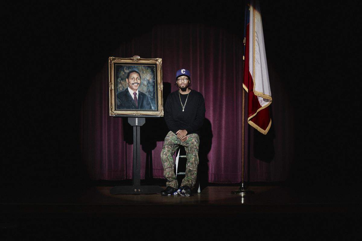 David J. Butler, posing beside a photo of his father in Butler High’s auditorium.