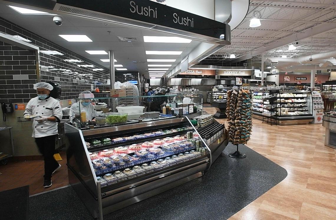 A sushi chef stocks the shelf at the Harris Teeter in the Park Road Shopping Center on opening day Wednesday after the store underwent a year of renovations.