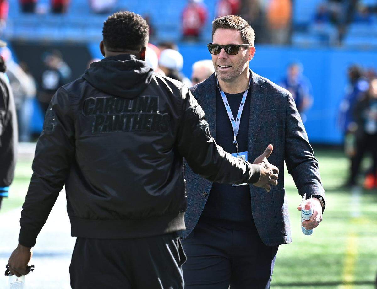 Former Carolina Panthers linebacker Thomas Davis, back to camera, greets then-assistant general manager Dan Morgan, right, along the team’s sideline at Bank of America Stadium in Charlotte, NC on Sunday, January 7, 2024. On Monday, January 8, 2024, team general manager Scott Fitterer was fired after three seasons following the team’s 9-0 loss to the Tampa Bay Buccaneers.