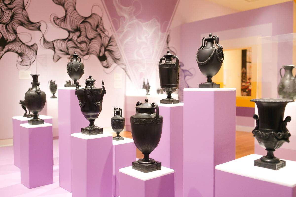 Mint Museum exhibition designer HannaH Crowell tried to bring the black sculptures in the “Classic Black” exhibit to life with warm background colors such as orange, pink, purple and yellow. Local artist Owl’s line drawings are visible in the background.