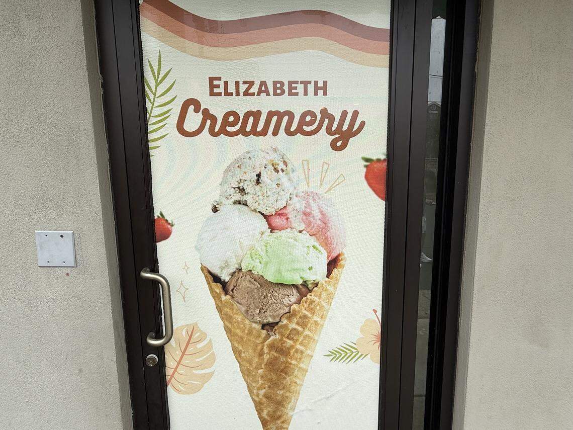 A close-up of a window graphic for Elizabeth Creamery featuring a large, colorful waffle cone with multiple scoops of ice cream and fresh strawberries.