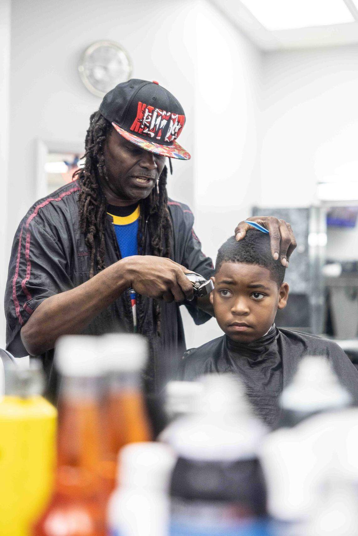 Rodney Thomas-Bey, left, cuts Dallas Hill’s hair at Anderton Barber & Stylists. 