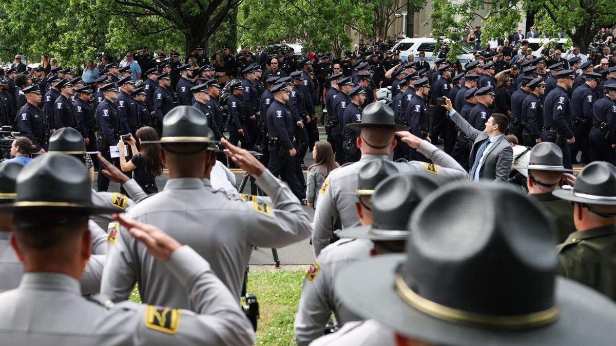 Law officers salute as a horse-drawn carriage carries the body of officer Joshua Eyer to First Baptist Church on Friday, May 3, 2024. Officer Eyer was killed while serving a warrant in east Charlotte on Monday, April 29, 2024