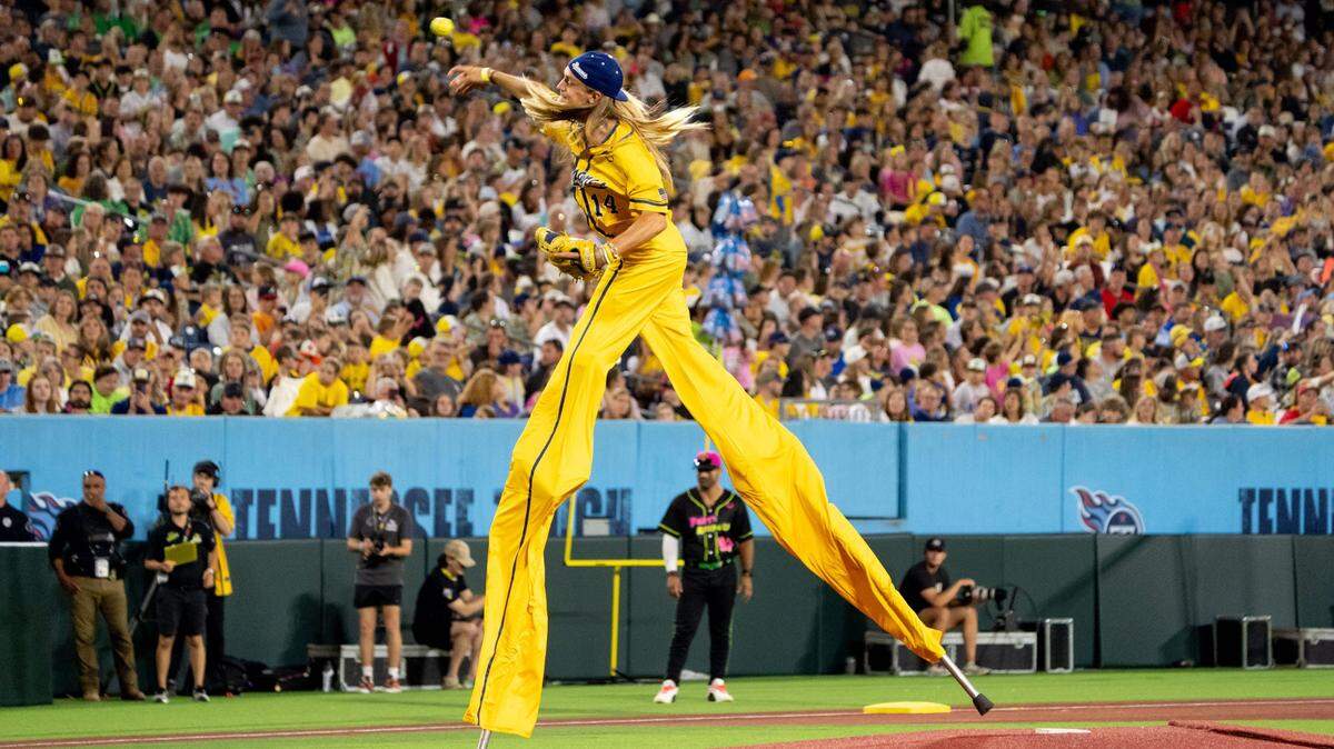 Savannah Bananas player Dakota Albritton (14) pitches during the sixth inning of a mid-May game against the Party Animals at Nissan Stadium in Nashville.