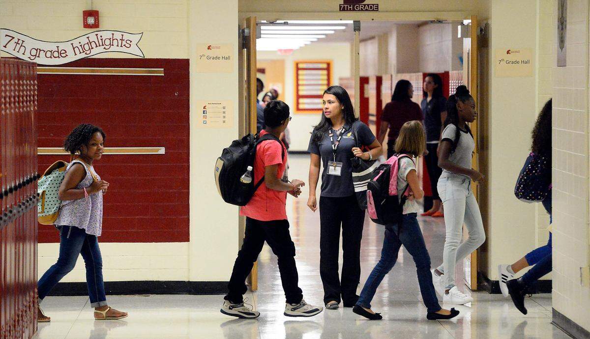 Charlotte-Mecklenburg Schools students will return for the start of the 2024-2025 school year next week. In this file photo, Quail Hollow Middle School ESL teacher Yeimy Penagos, center, watches as students change classes during the first day of the school year in 2016.
