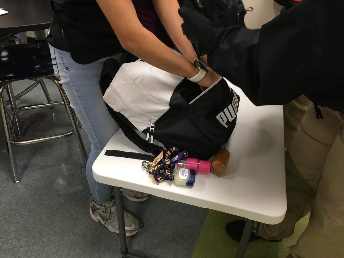 A student removes items from a book bag during a gun search at Rocky River High on Tuesday.