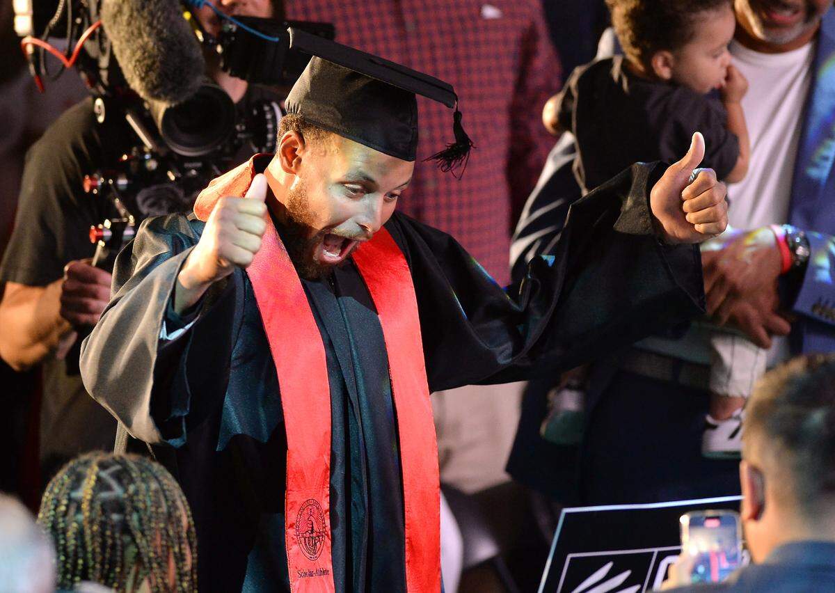 Stephen Curry reacts to his son, Canon Curry, holding a sign as Stephen Curry walked down the aisle for his graduation ceremony at Davidson College on Wednesday, August 31, 2022 in Davidson, NC. In addition to receiving his diploma, Curry was inducted into the school’s hall of fame and also had his iconic number 30 jersey retired.