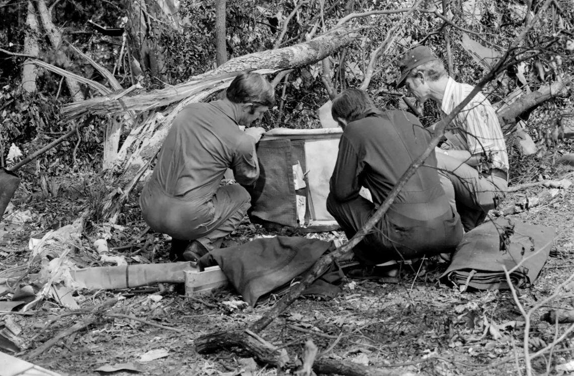 Rescuers look at a suitcase that was found in the woods after the crash of Eastern Flight 212 in Charlotte on Sept. 11, 1974.