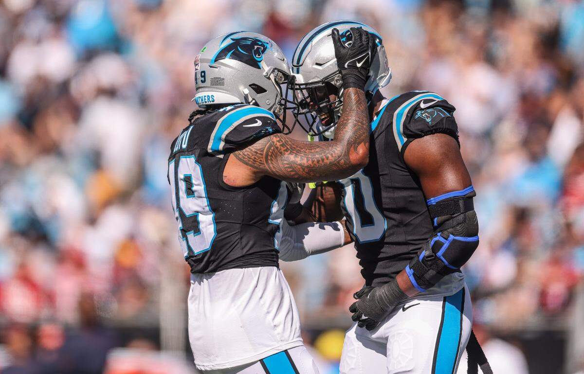 Carolina Panthers linebacker Brian Burns, right, and Carolina Panthers linebacker Frankie Luvu celebrate a sack against the Houston Texans in Charlotte in 2023. Both men were reported to be leaving the Panthers Monday -- Burns via trade and Luvu via a new contract with Washington.