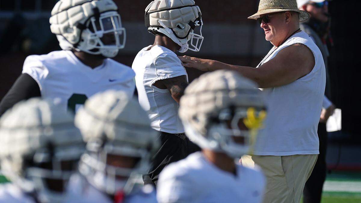 Charlotte 49ers head coach Biff Poggi, right, stops to speak to a player during a change in drills during the team’s first summer training camp practice on Friday, August 3, 2024.
