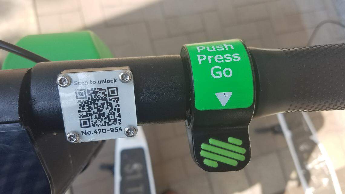 The controls for a Lime scooter, showing the QR code to scan and the thumb-push accelerator to operate the throttle.