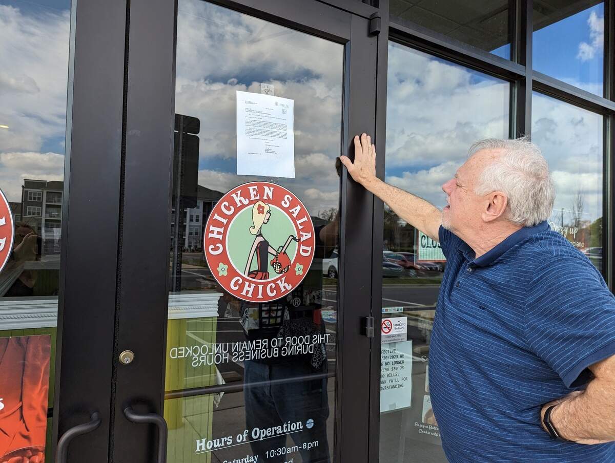 Tom Reda of Charlotte reads the notice of default posted on the door Monday at Chicken Salad Chick at 2114 Freeman Park Drive in Charlotte.