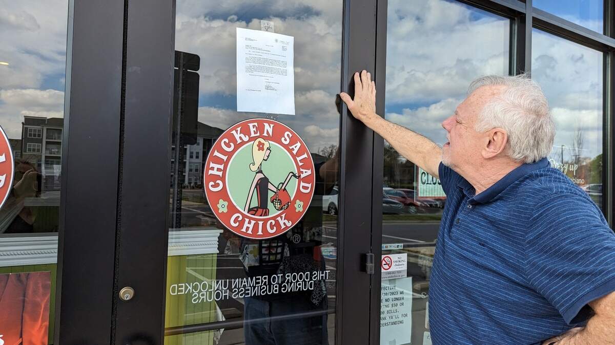 Tom Reda of Charlotte reads the notice of default posted on the door Monday at Chicken Salad Chick at 2114 Freeman Park Drive in Charlotte.