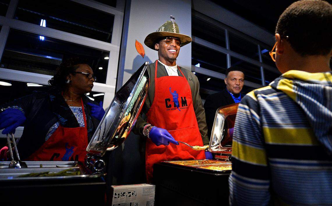 Cam Newton, center, serves macaroni and cheese to children during his “Cam’s Thanksgiving Jam,” event in 2017 at Topgolf Charlotte. Newton has been active in giving back to the community in his eight years in Charlotte.