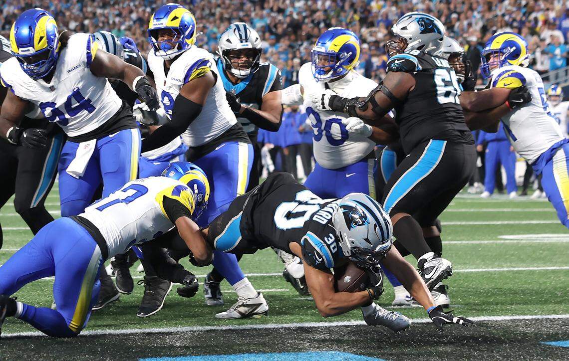 Carolina Panthers running back Chuba Hubbard, center, dives into the end zone for a touchdown during action against the Los Angeles Rams at Bank of America Stadium on Saturday, January 10, 2026. 