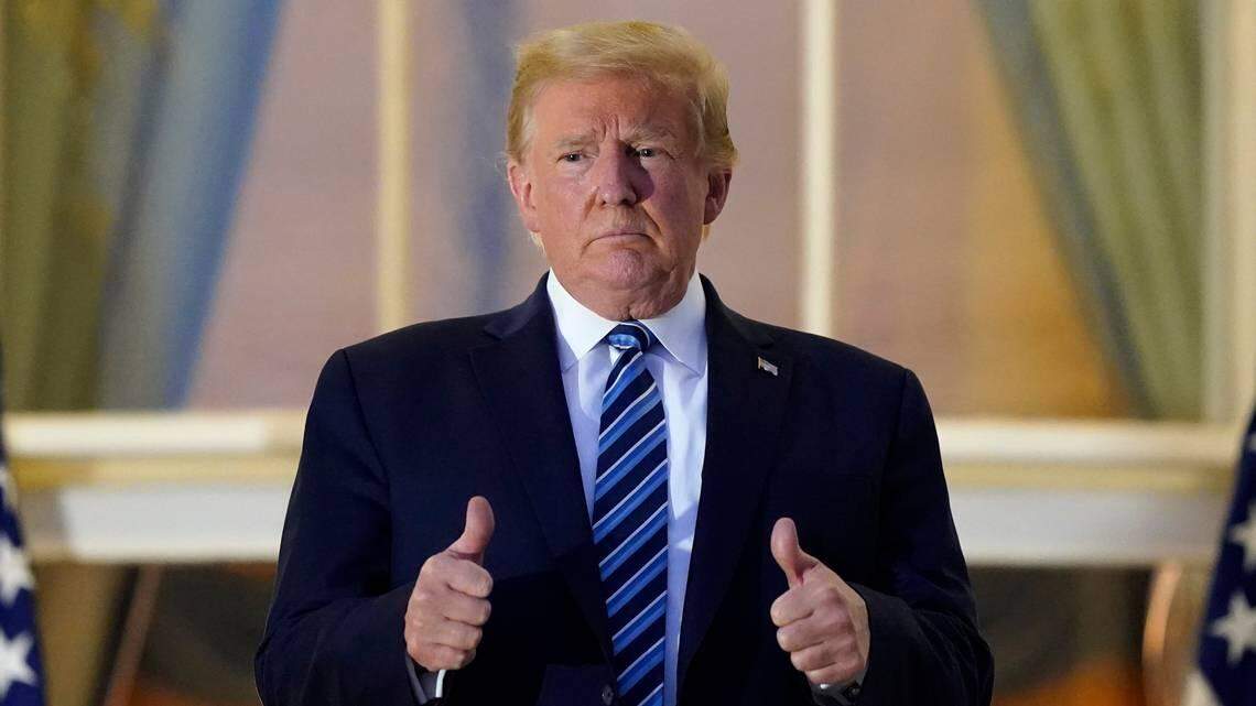 President Donald Trump stands on a balcony after returning to the White House on Monday night from Walter Reed National Military Medical Center where he was treated for COVID-19.