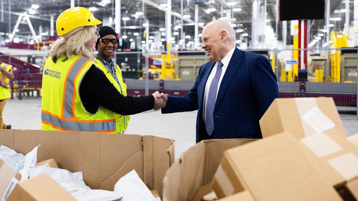 Postmaster General Louis DeJoy talks Nov. 9 with employees. The United States Postal Service is pausing a restructure amid criticism.