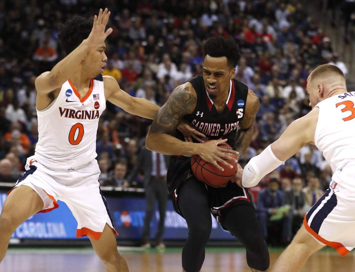 Gardner-Webb’s David Efianayi (11) drives by Virginia’s Kihei Clark (0) and Jack Salt (33) during the first half of Gardner-Webb’s game against Virginia Friday. Virginia won, 71-56.