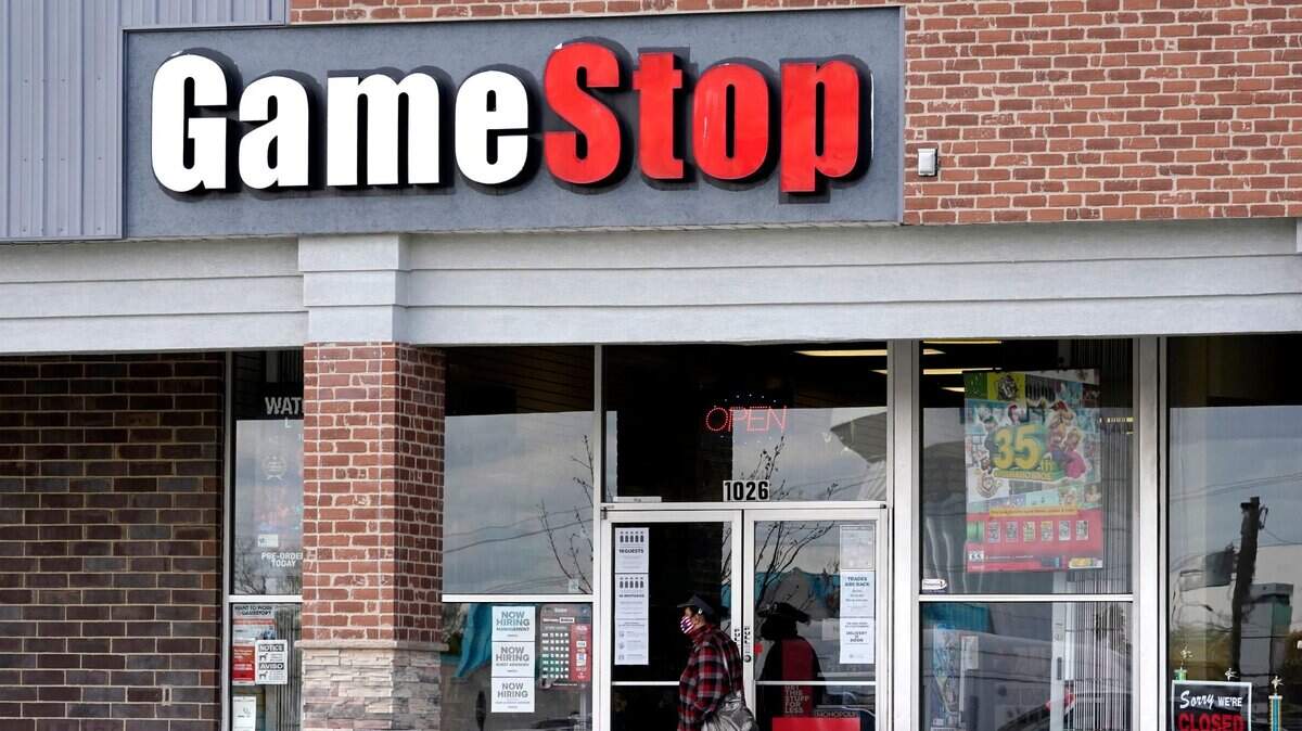 FILE - In this Oct. 15, 2020 file photo, a woman wears a face mask as she walks past a GameStop store in Des Plaines, Ill. Two hedge funds are bowing out of their short positions on the money-losing video game retailer. Citron Research’s Andrew Left said in a video posted on YouTube that his company is going to become more judicious in shorting stocks. Melvin Capital is also exiting GameStop, with manager Gabe Plotkin telling CNBC that the hedge fund was taking a significant loss. (AP Photo/Nam Y. Huh, File)