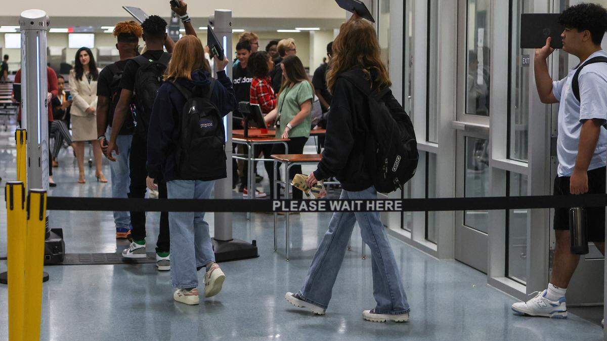 Students raise their laptops as they walk through metal detectors during the first day of school at Palisades High School, a brand new CMS campus, on Monday, August 29, 2022 in Charlotte, NC.