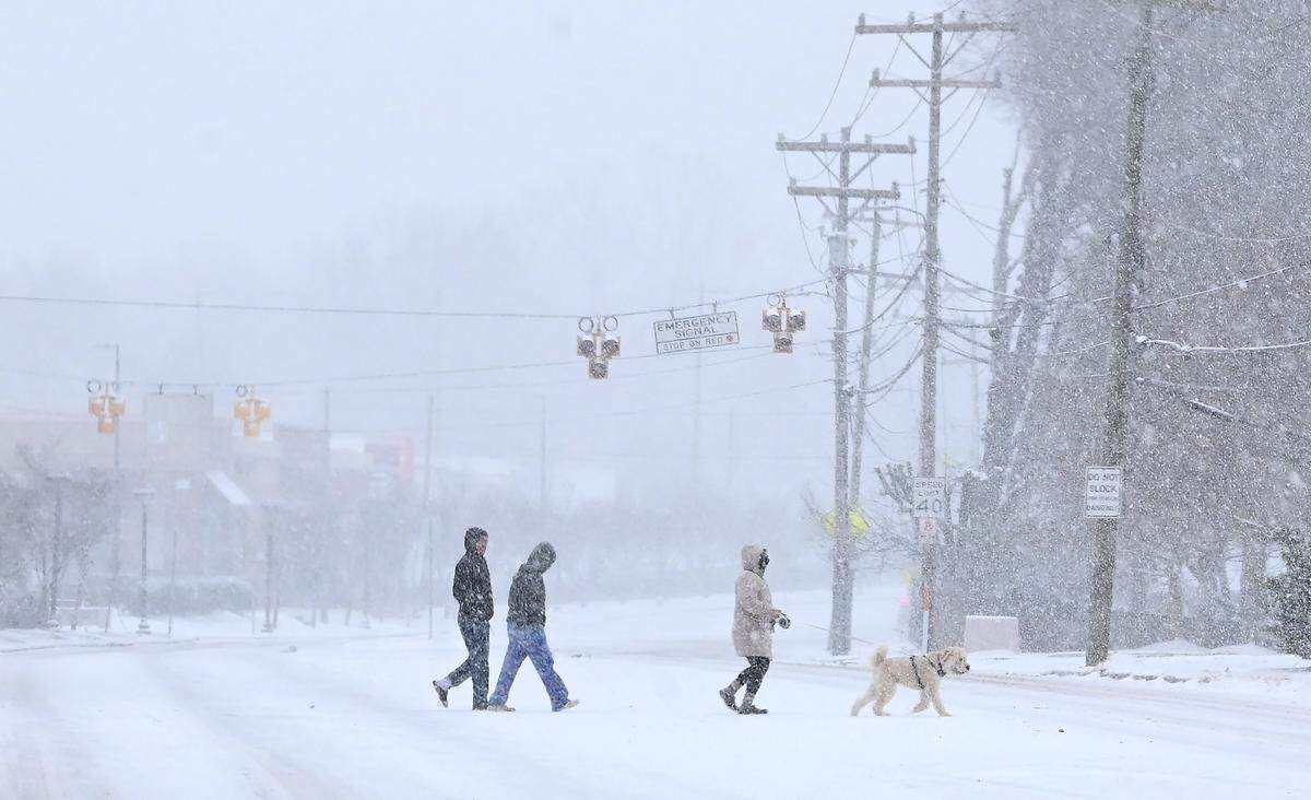 The snow falls as people enjoy a walk with their dog along Monroe Road in Charlotte, NC on Saturday, January 31, 2026.