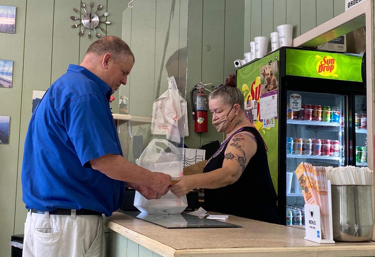 A customer picks up his carryout order Tuesday at Oakhurst Grill.