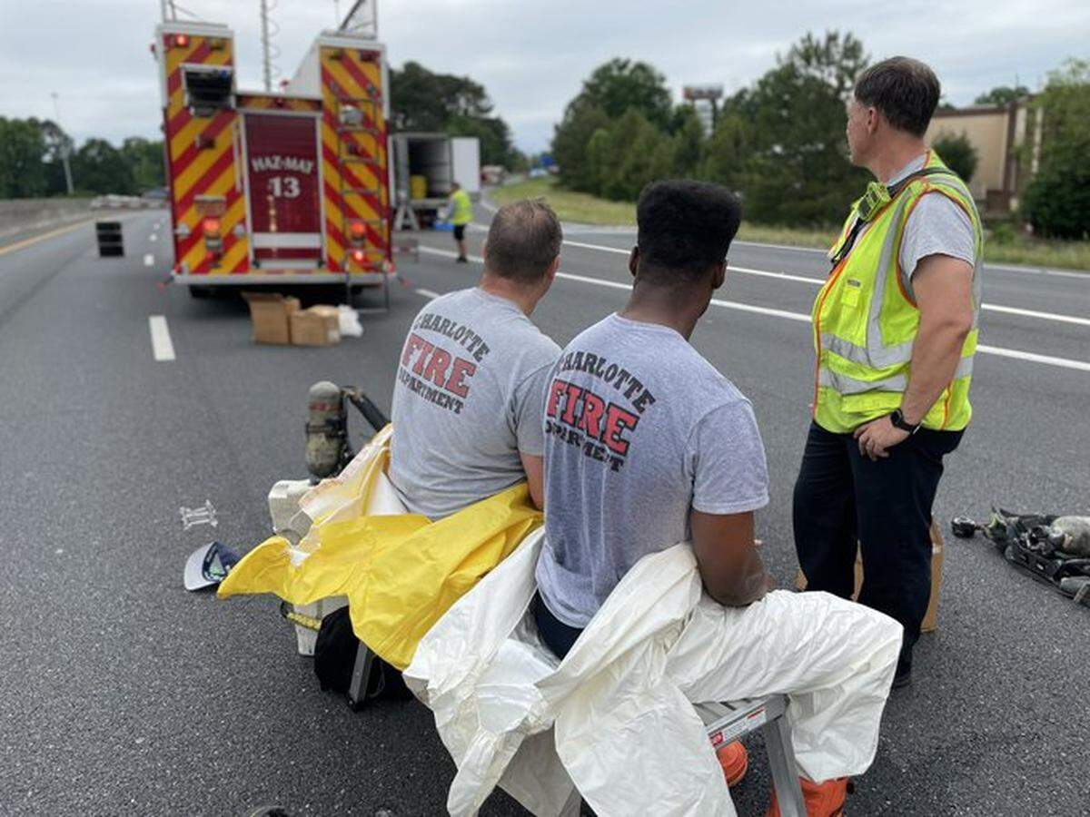 Charlotte firefighters take a respite after helping clean up a chemical spill on Interstate 77 southbound at Nations Ford Road exit 4 on Wednesday, May 25, 2022.