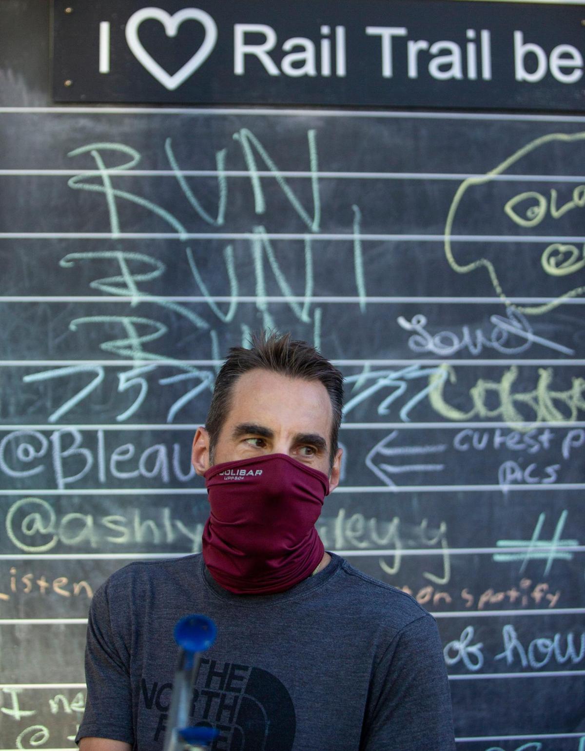 Paul Neumann walks past a chalk board along the Rail Trail in Charlotte, NC on Saturday, July 11, 2020. Neumann trains for marathons regularly and runs along the Rail Trail most days and noticed trash along the route. Once he started picking up trash weekly he made it his mission to regularly collect trash along the path