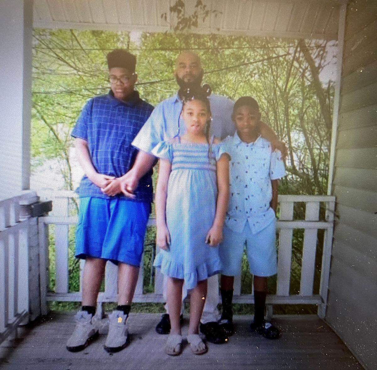 In this undated photo, Kevin Boston stands with his three children. Boston, a 45-year-old single father, was shot and killed by Charlotte-Mecklenburg Police officers Sunday, June 26, 2022. Police say Boston, a suspect in an armed robbery, fired a gun at officers.