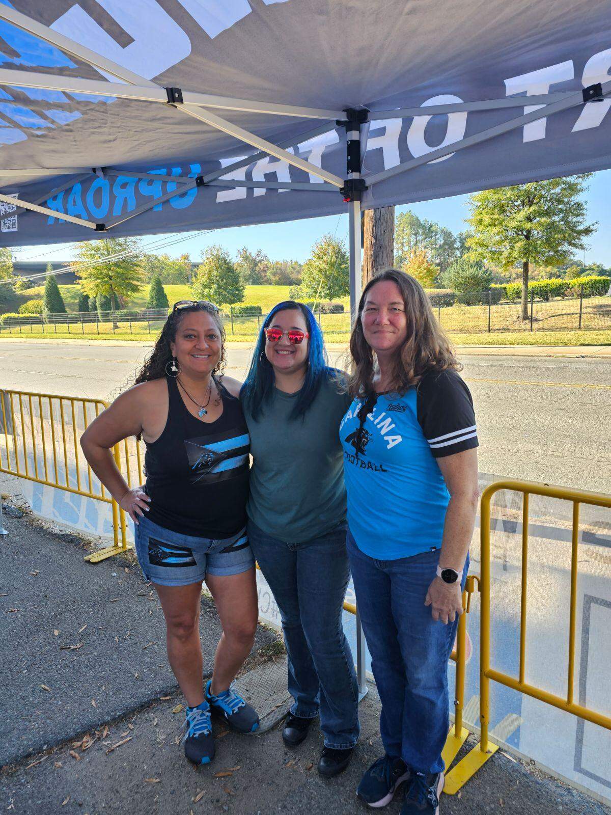 Erika Moulton, left, and friends pose for a photo at a Roaring Riot tailgate before a Carolina Panthers game. Moulton wears clothing with a flag stitched on — one that merges the design of the Puerto Rican flag with the colors and logo of the Panthers team logo: “I wear my Hispanic pride at every game,” she said.