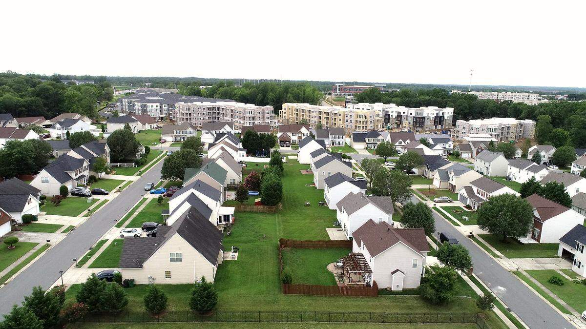 The Tapestry University City apartments development rises behind the homes in Rocky River Village in the University City area of Charlotte, NC on Thursday, July 8, 2021.
