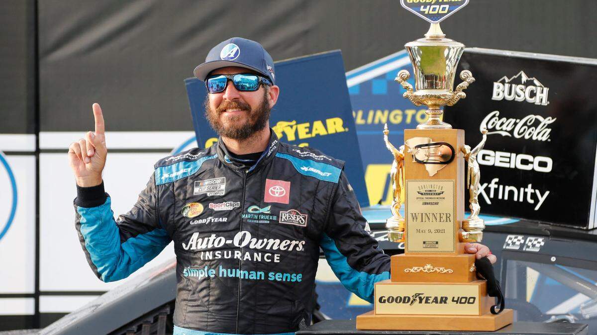 Martin Truex Jr. stands with his trophy in Victory Lane after winning the NASCAR Cup Series auto race at Darlington Raceway, Sunday, May 9, 2021, in Darlington, S.C. (AP Photo/Terry Renna)