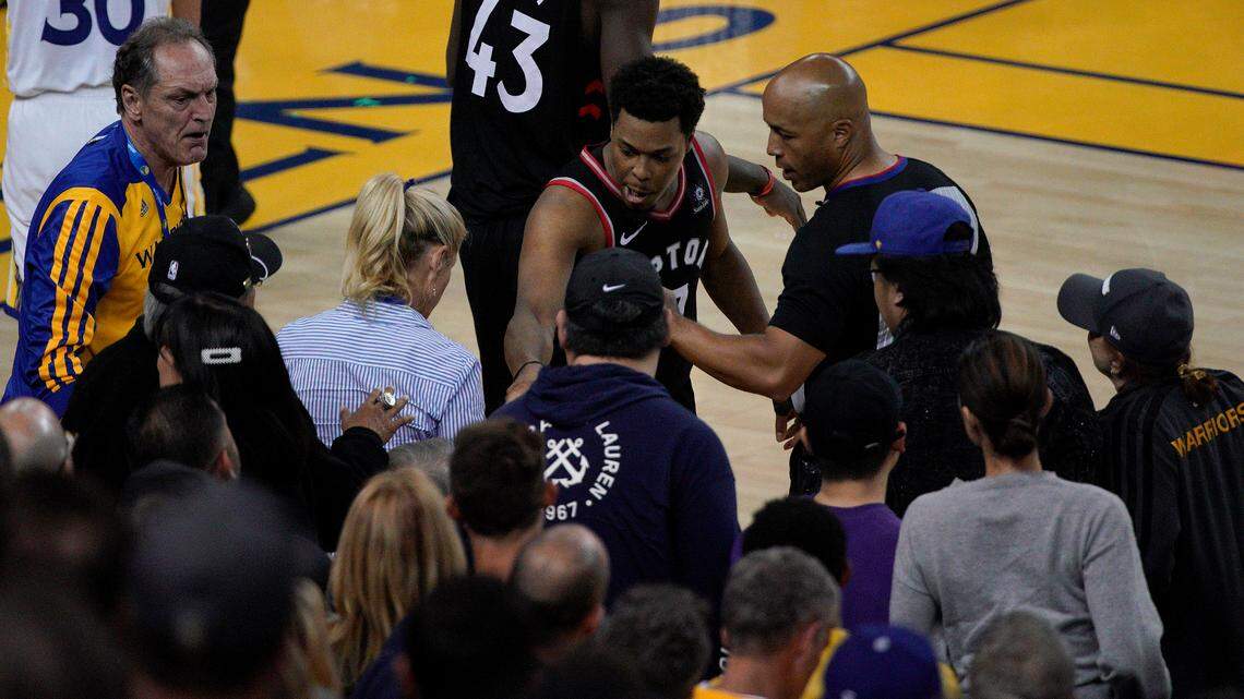Toronto Raptors guard Kyle Lowry, middle, gestures next to referee Marc Davis (8) near the front row of fans during the second half of Game 3 of basketball’s NBA Finals between the Golden State Warriors and the Raptors in Oakland, Calif., Wednesday, June 5, 2019. A fan seated courtside for Game 3 of the NBA Finals was ejected after shoving Lowry when the Raptors star crashed into a row of seats while trying to save a ball from going out of bounds on Wednesday night. (AP Photo/Tony Avelar)