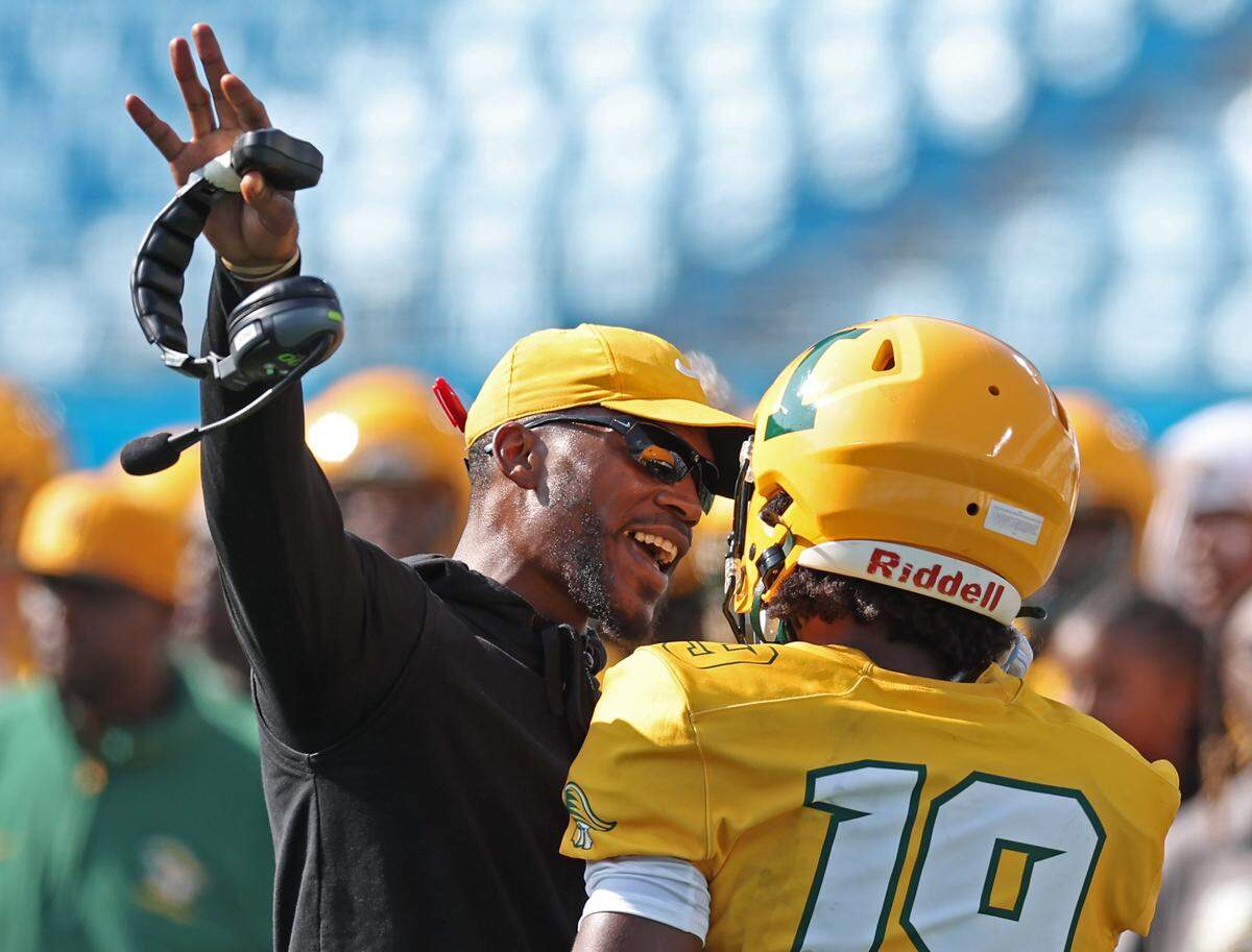 Independence Patriots head coach D.J. McFadden, left, talks with wide receiver/tight end Wisdom Whipper-Daniel, right, during action against Myers Park on Aug. 22, 2024, at Bank of America Stadium. The teams were competing in the Keep Pounding High School Classic.