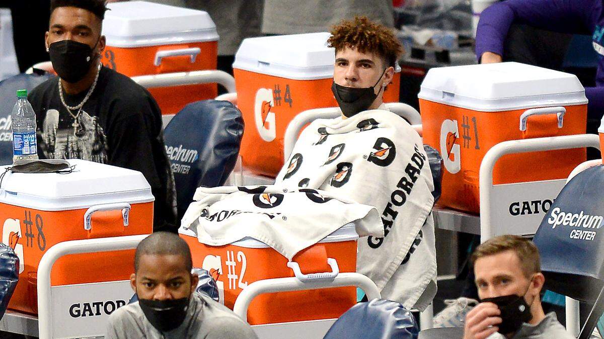 Charlotte Hornets guard LaMelo Ball, center, sits on the team’s sideline wrapped in Gatorade towels while watching the team play the Cleveland Cavaliers at Spectrum Center in Charlotte, NC on Wednesday. The Cavaliers defeated the Hornets 103-90.