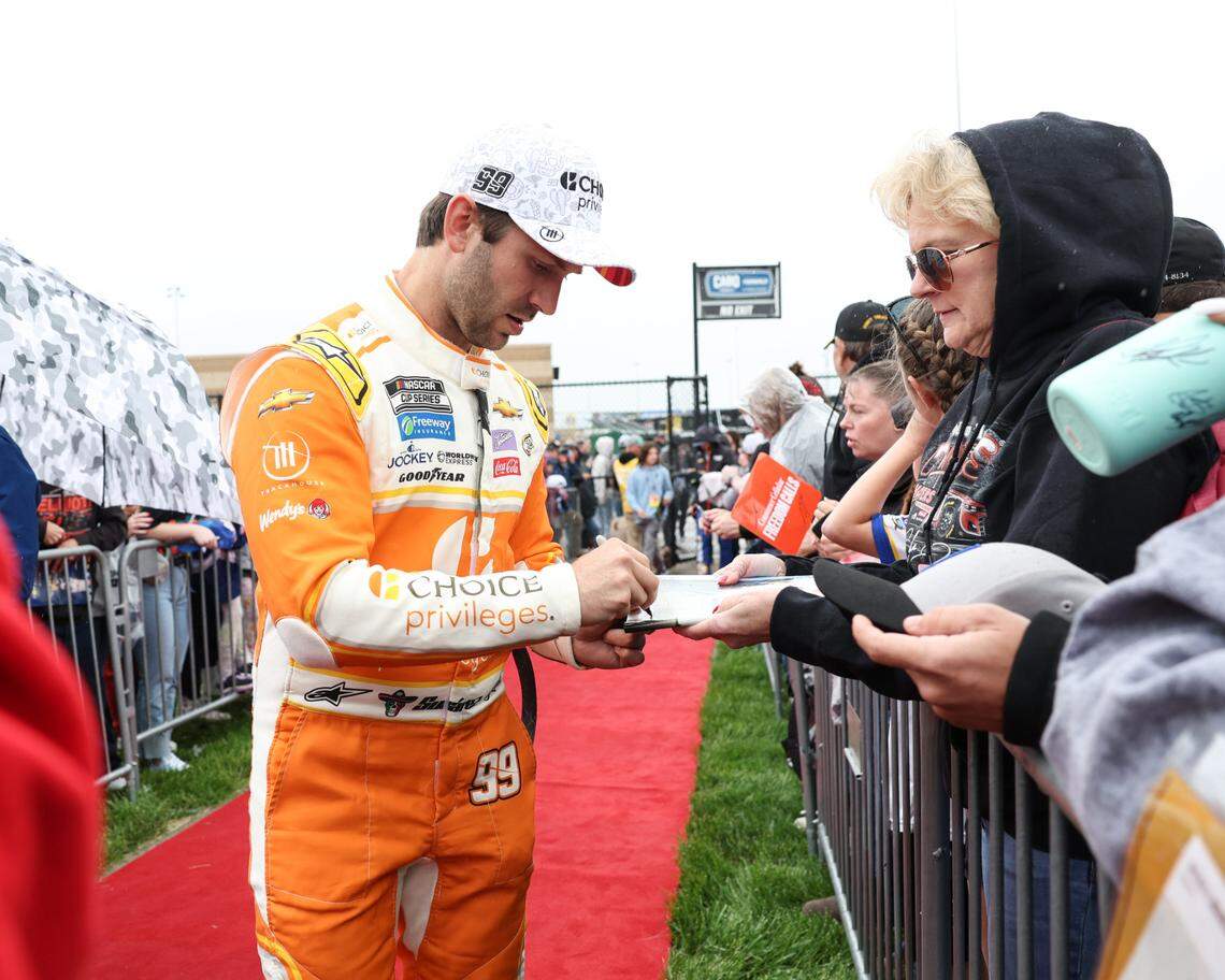 May 5, 2024; Kansas City, Kansas, USA; NASCAR Cup Series driver Daniel Suarez (99) signs autographs during pre-race rain at Kansas Speedway.