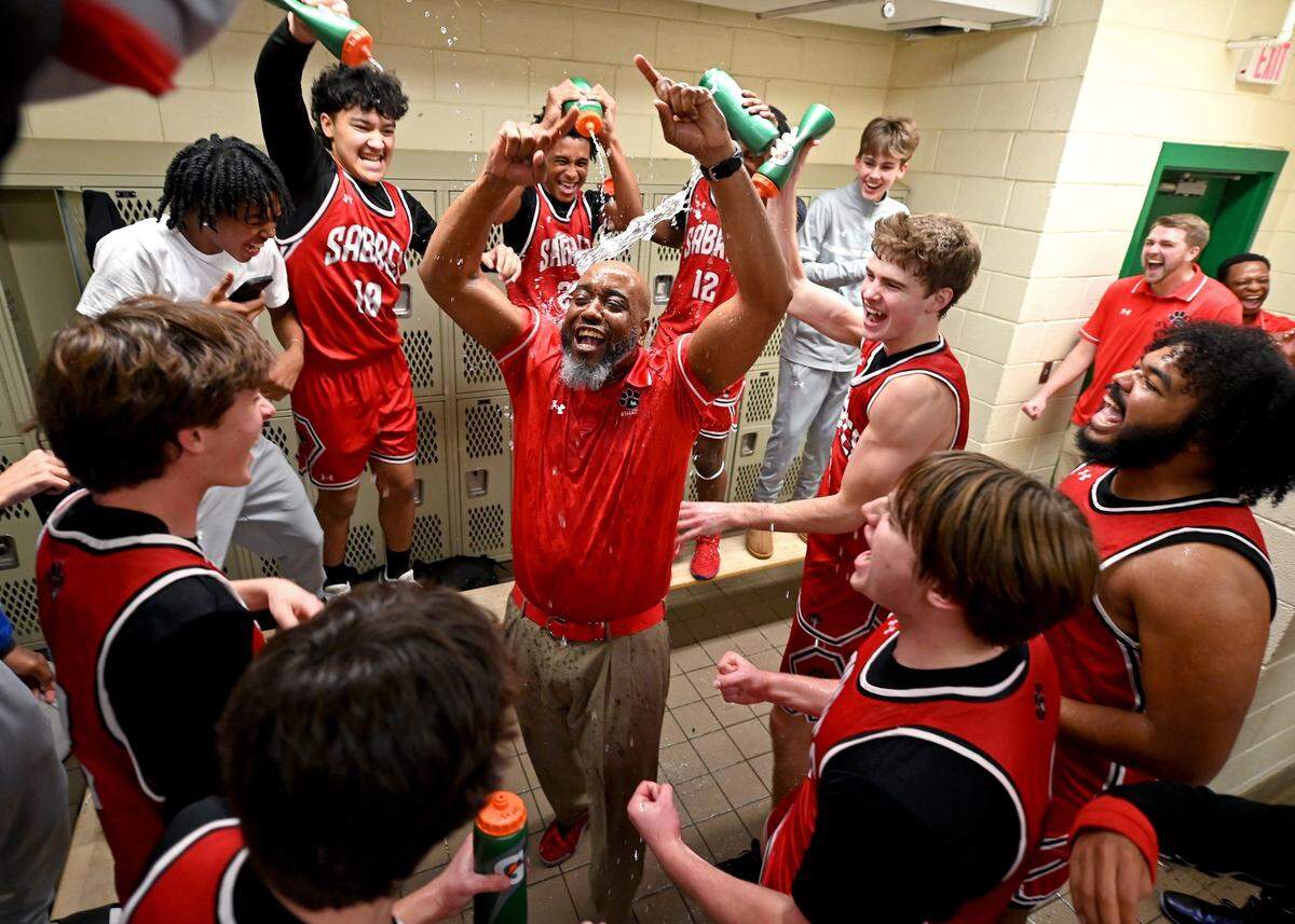 South Meck head boys basketball coach Christopher McDonald, center, is doused in water as he and his team celebrate their win over Myers Park on Friday, January 17, 2025 at Myers Park High in Charlotte, NC.