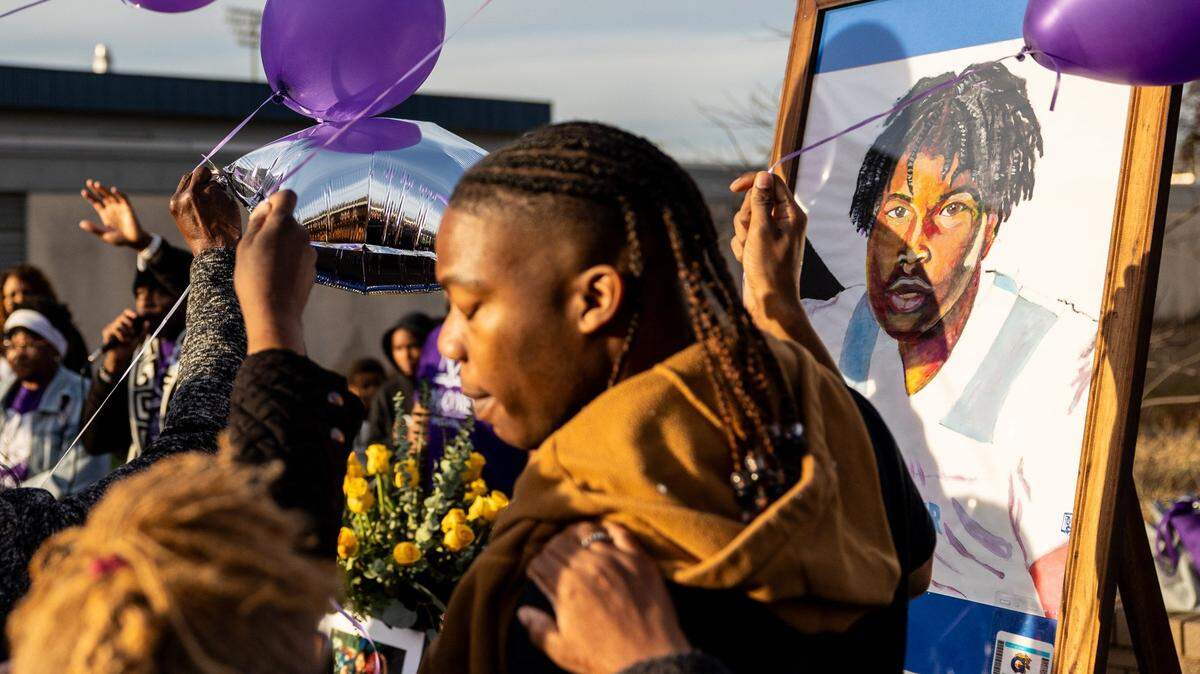 Family members of Johnnie McClendon gather around a table with portraits of the freshman student during a vigil at Garinger High School in Charlotte on Friday, December, 2023.