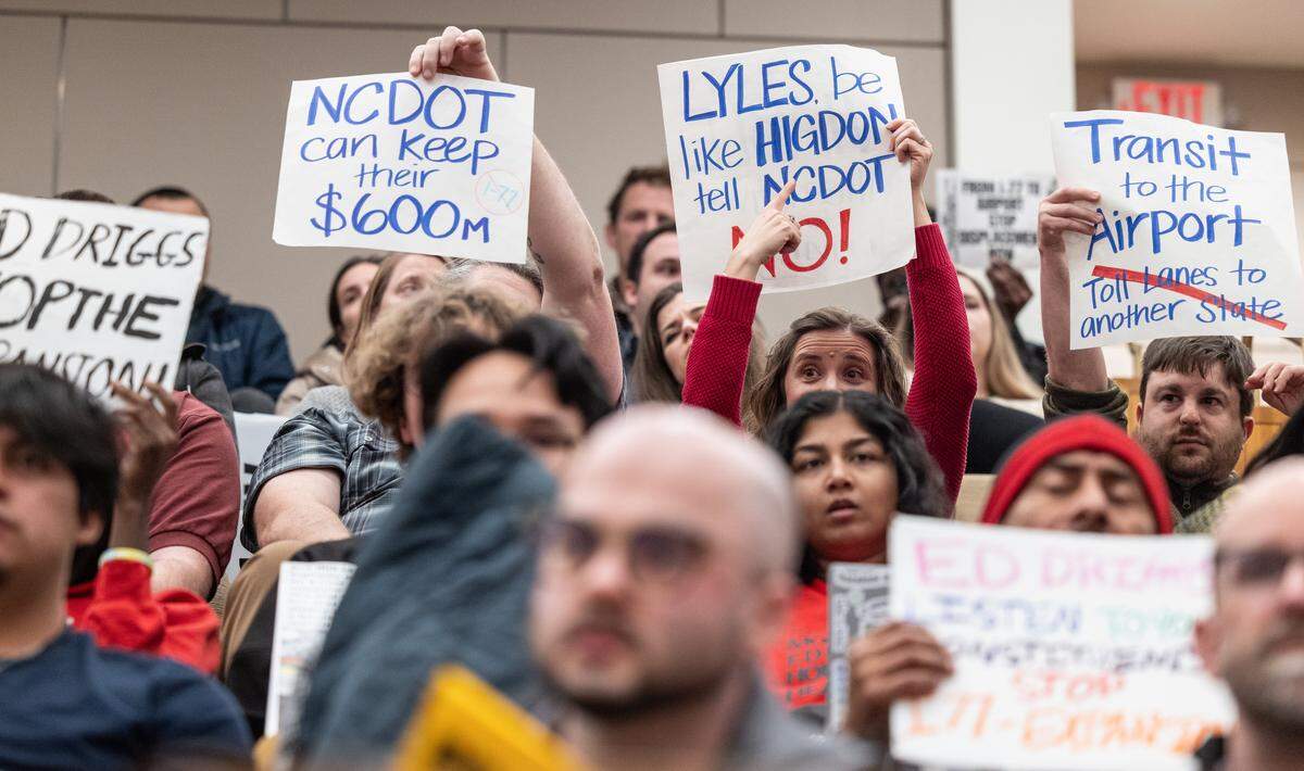 Residents concerned about the I-77 project hold up signs during the City Council meeting at the Charlotte-Mecklenburg Government Center in Charlotte, N.C., on Monday, February 23, 2026.