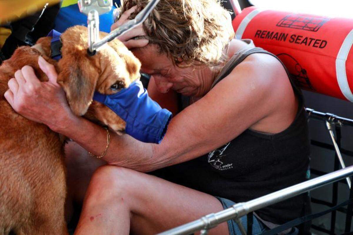A woman in Eastern North Carolina comforts her dog after they were rescued by a U.S. Customs and Border Protection Air and Marine Operations helicopter on Monday.