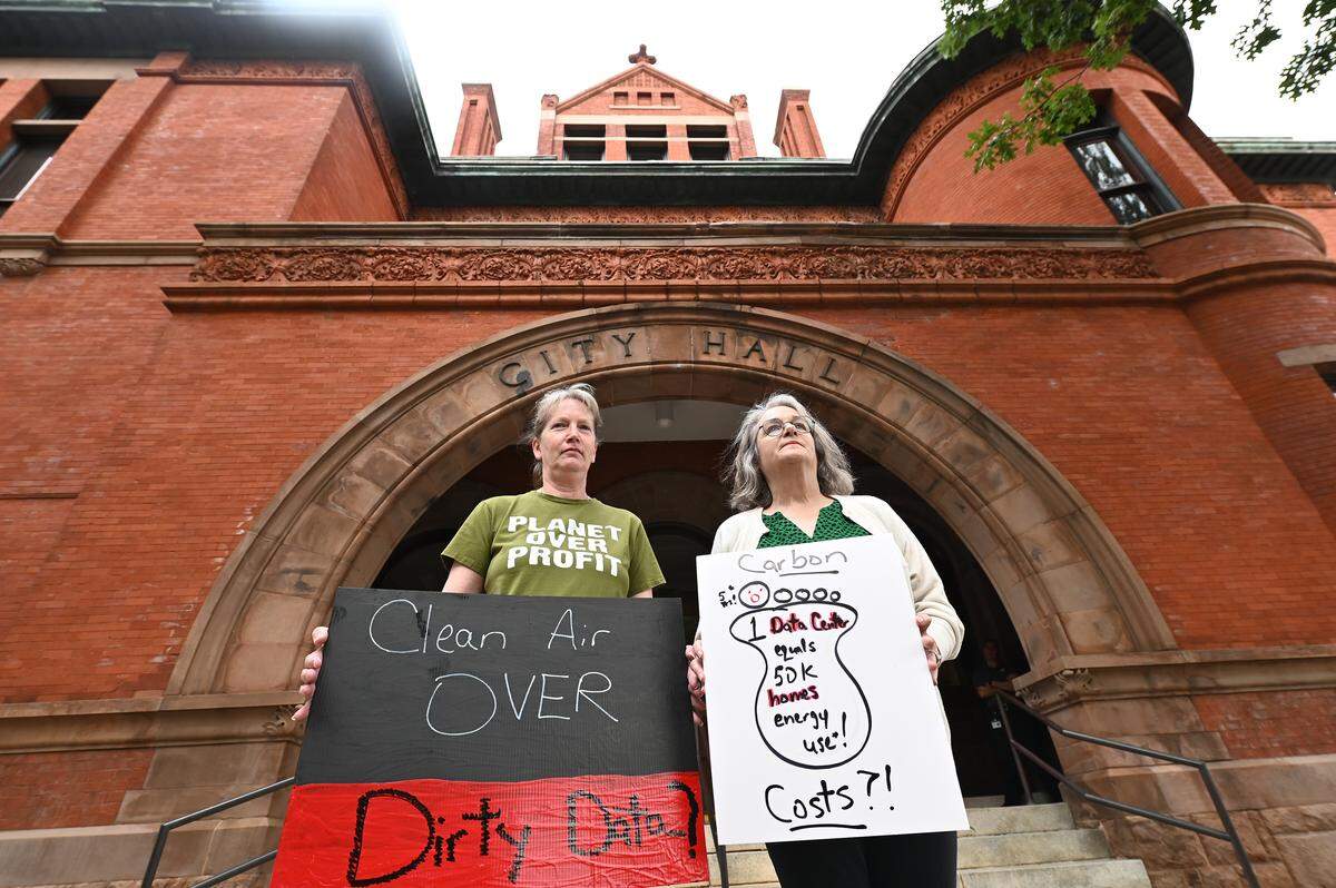Dawn Simmons, left, and Lynne Taylor, right, held signs outside Statesville City Hall on Monday, Sept. 15, 2025, protesting a planned western Iredell County data center.