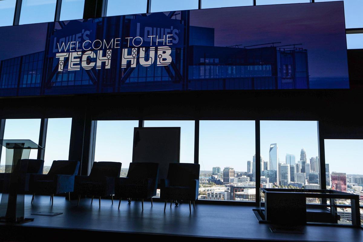 Lowe’s new Tech Hub in South End features a two-level auditorium with stage and massive screen and uptown Charlotte’s skyline in the background.