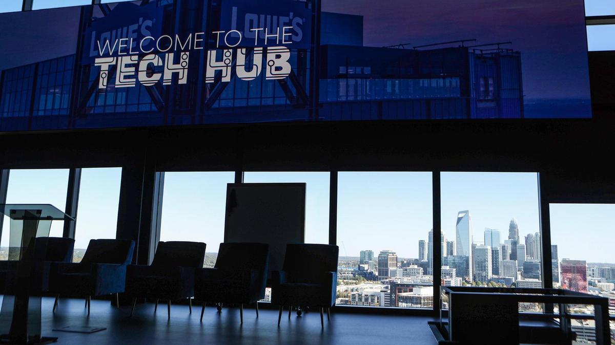 Lowe’s new Tech Hub in South End features a two-level auditorium with stage and massive screen and uptown Charlotte’s skyline in the background.