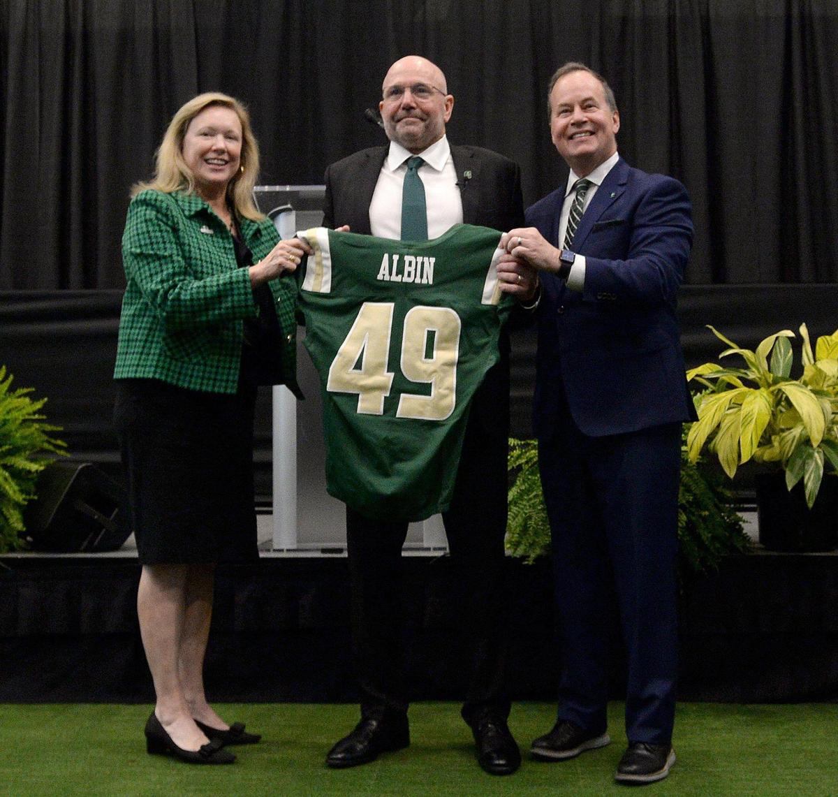 UNC Charlotte chancellor Sharon Gaber (left) and 49ers athletic director Mike Hill (center) present new football coach Tim Albin with a Charlotte jersey. The Charlotte 49ers officially announced Tim Albin, a two-time Mid-American Conference coach of the year, as the new head coach of their football team on Monday, Dec. 9, 2024. About 200 people attended the announcement.