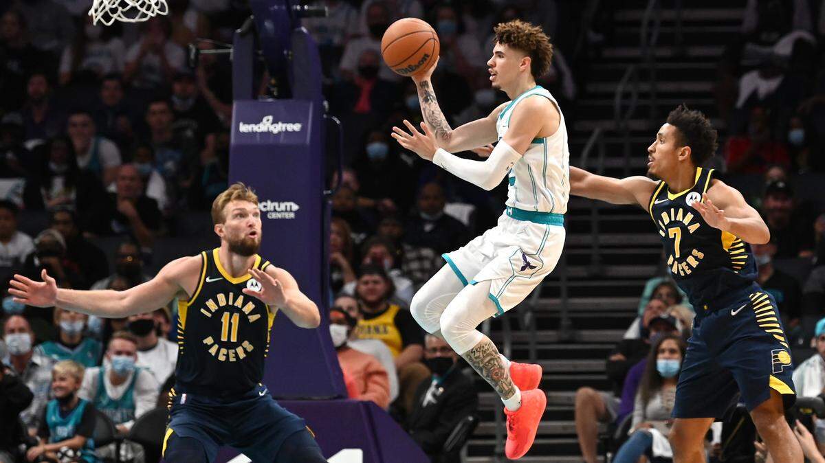 Charlotte Hornets guard LaMelo Ball, center, glides between Indiana Pacers defenders center Domantas Sabonis, left and guard Malcolm Brogdon, during the fourth quarter action at Spectrum Center in Charlotte, NC on Wednesday, October 20, 2021. The Hornets defeated the Pacers 123-122, with Ball scoring 31 points.